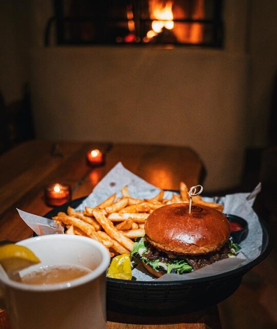 Burger and fries with fireplace in background.