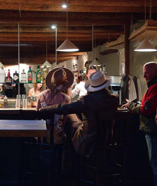 Fashionable couple in hats sitting at a bar.