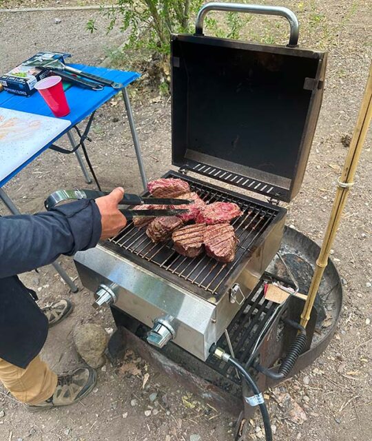 Large steaks on an outdoor grill.