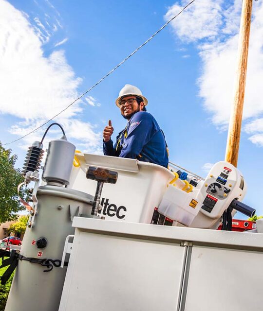 Kit Carson Electric lineman in bucket giving a thumbs up.