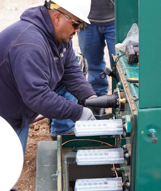 Electric lineman working in a ground electric box.
