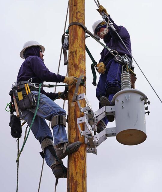Linemen on pole making electric repairs.
