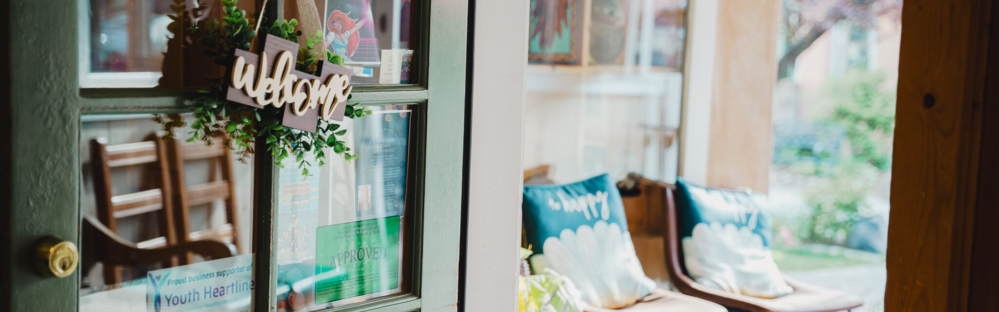 A cute wooden "Welcome" sign dons a windowed door.