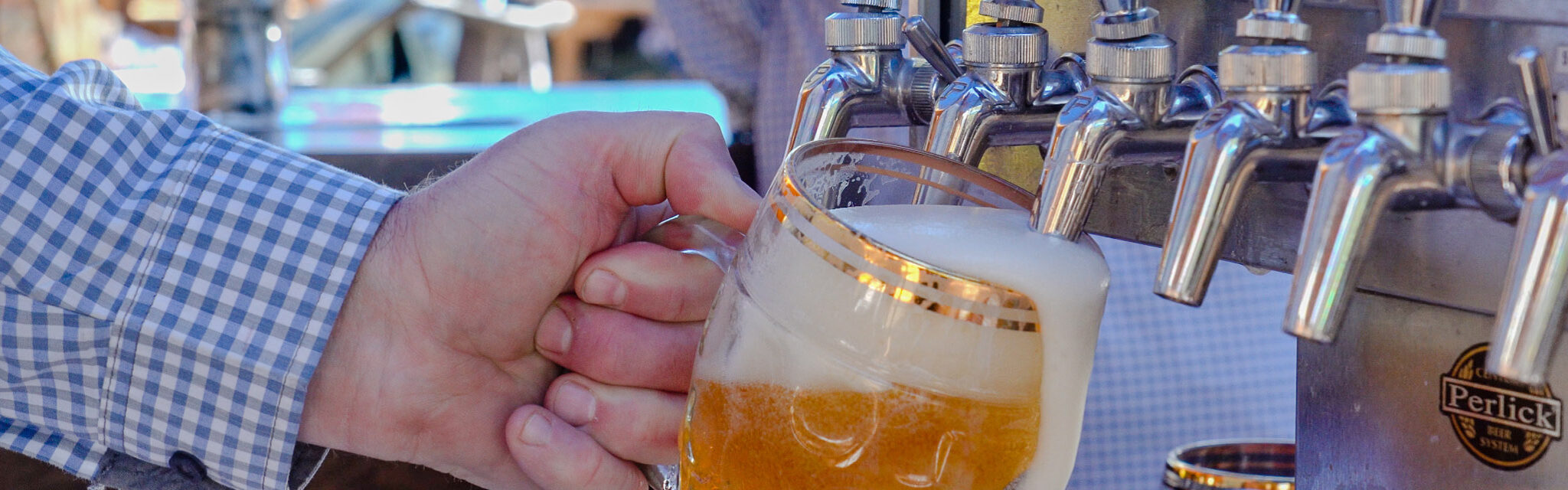 A beer being poured from a tap in a krug style mug.