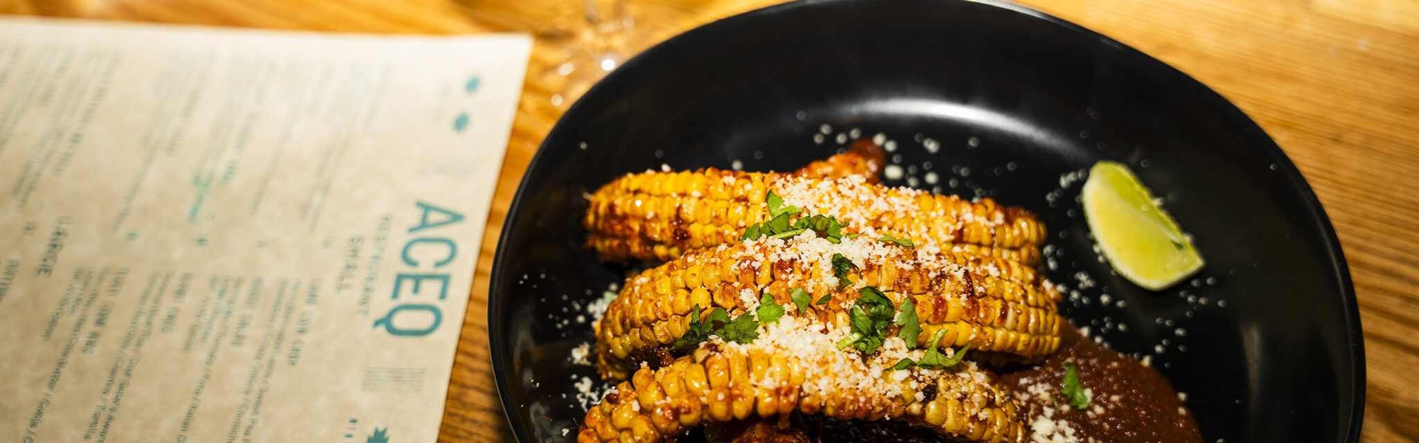 Mexican corn and refried black beans served on a black plate.