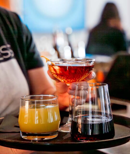 Three craft cocktails and wine with server.