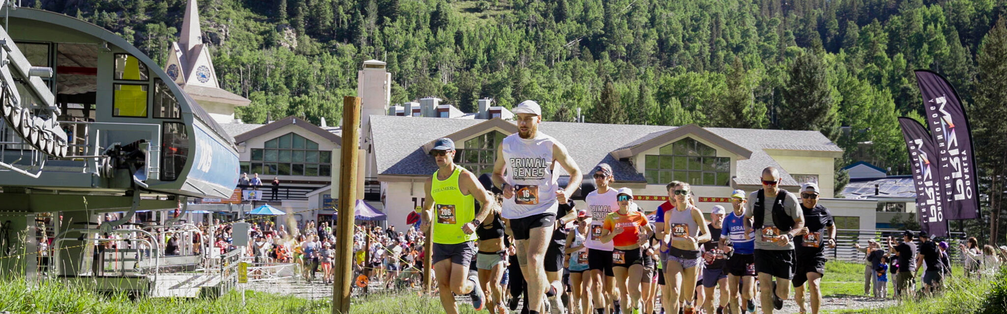 A group of runners start in a pack at the beginning of a trail race.
