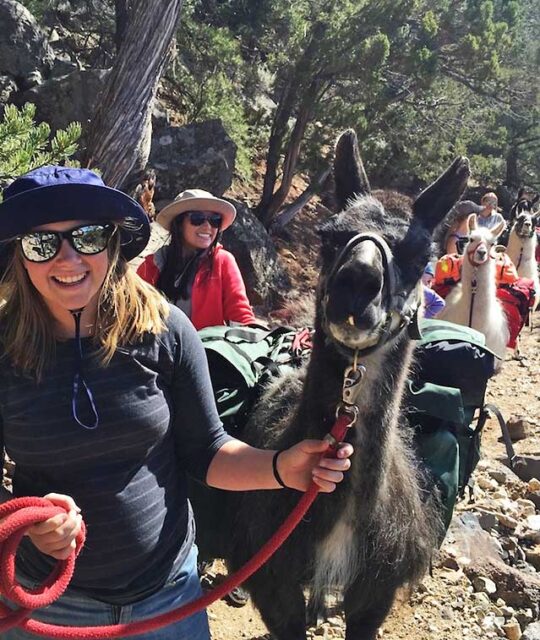 Women smiling while trekking with llamas at the Rio Grande Gorge.